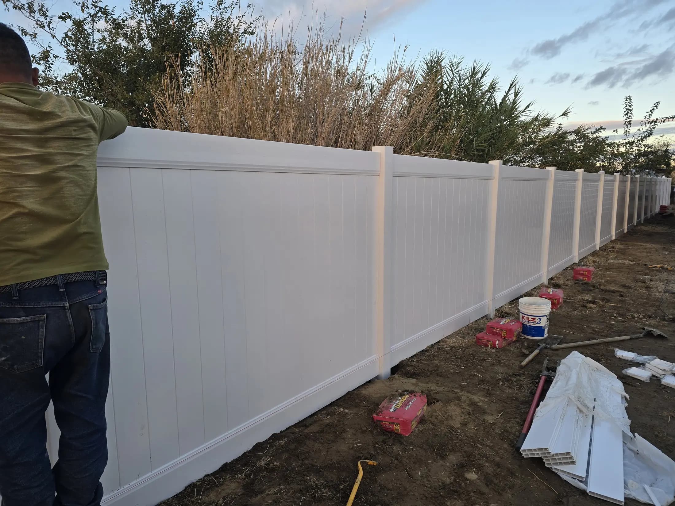 Long white vinyl privacy fence run along a property line